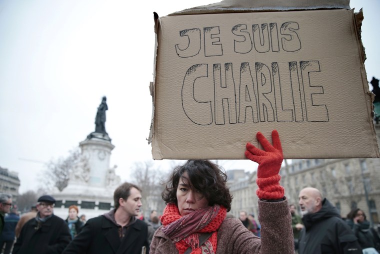A woman holds up a placard that reads in French, \"I am Charlie\" as she and others gather at the Place de la Republique in the French capital Paris, on Jan. 7, 2015, following an attack by unknown gunmen on the offices of the satirical weekly, Charlie Hebd