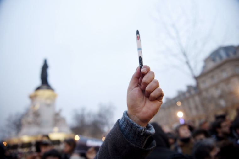 A man raises a pen during a rally in support of the victims of today's terrorist attack on French satyrical newspaper Charlie Hebdo at the Place de la Republique in Paris, on Jan. 7, 2015.