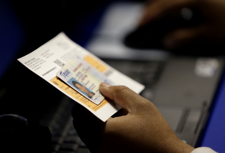 An election official checks a voter's photo identification at an early voting polling site on Feb. 26, 2014 in Austin, Texas. (Photo by Eric Gay/AP)