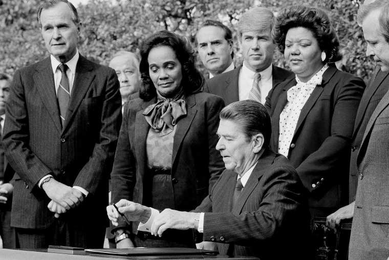President Ronald Reagan signs the bill making Martin Luther King Jr.'s birthday into a national holiday, as Coretta Scott King watches on Nov. 2, 1983, in Washington.