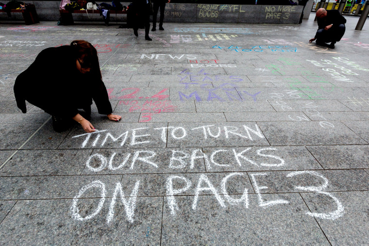 \"No More Page 3\" campaign write messages on the pavement to David Dinsmore, The Sun editor, outside the News UK head office 'No More Page Three' demonstration, on Nov. 16, 2014 in London, Britain. (Photo by Vickie Flores/Rex Features via AP)