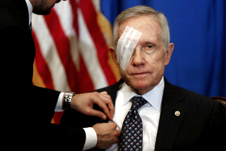 An aide attaches a microphone as U.S. Senate Minority Leader Harry Reid sits down for a news conference in his office at the U.S. Capitol in Washington Jan. 22, 2015. (Photo by Jonathan Ernst/Reuters)