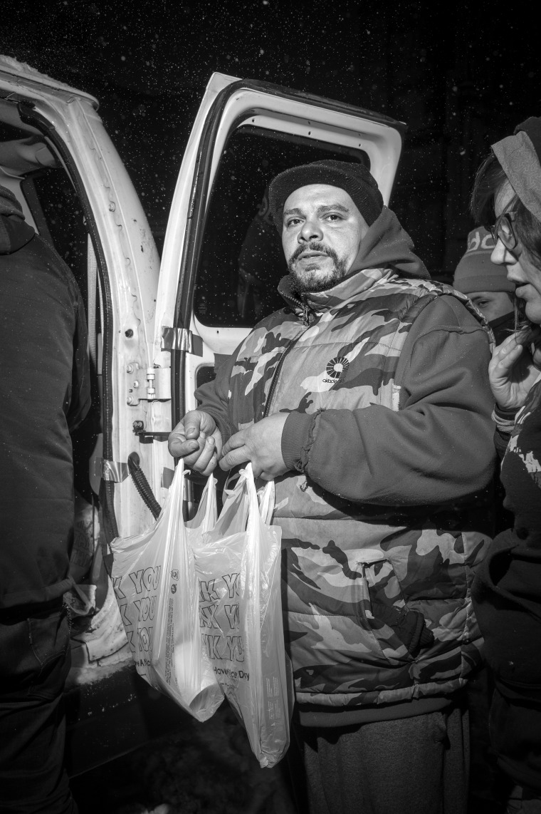 Homeless man in front of the Cathedral of Saint John the Divine, with food received from the crew in the Coalition for the Homeless van before the streets of New York City were shut down for the approaching blizzard.