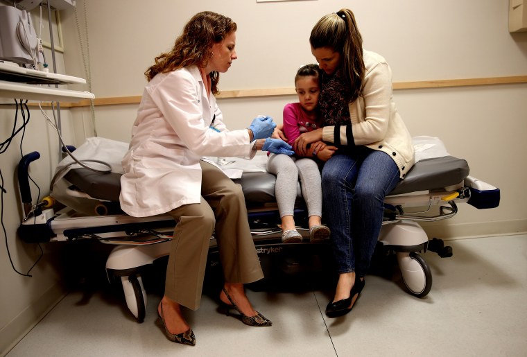 Miami Children's Hospital pediatrician Dr. Amanda Porro, M.D prepares to administer a measles vaccination to Sophie Barquin,4, as her mother Gabrielle Barquin holds her on Jan. 28, 2015 in Miami, Florida. (Photo by Joe Raedle/Getty)