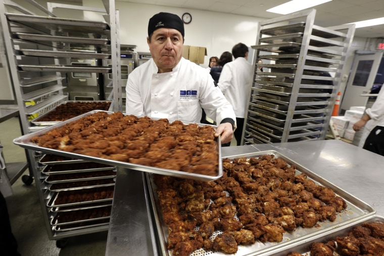 Patricio Gonzalez carries a tray of chicken wings while prepping food items at MetLife Stadium, Jan. 17, 2014, in East Rutherford, N.J., ahead of NFL football's Super Bowl XLVIII.