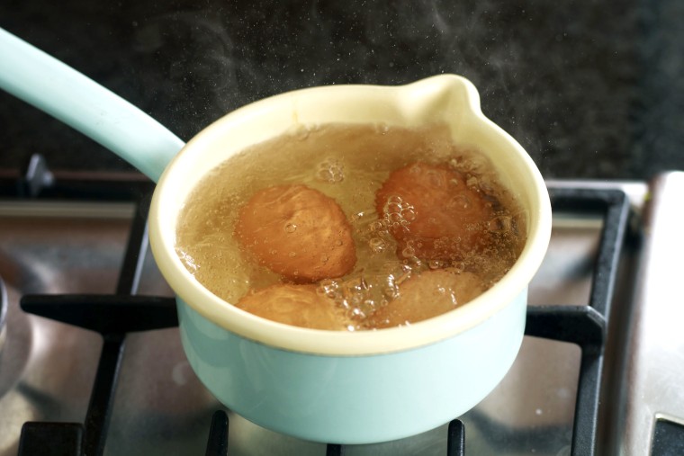 Eggs boiling in small saucepan.
