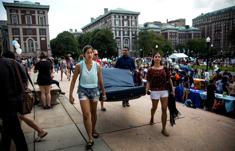 Emma Sulkowicz (L), a then-senior at Columbia University, carries a mattress with the help of three strangers, protesting the university's lack of action after she reported being raped, on Sept. 5, 2014 in New York City. (Photo by Andrew Burton/Getty)