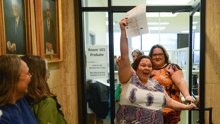 Eleanor Shue lifts her marriage license and yells in celebration as she and partner Jessica White emerge from the Probate Judges office after getting their marriage licenses in the Madison County Courthouse in Huntsville, Ala., on Feb. 9, 2015. (Photo by