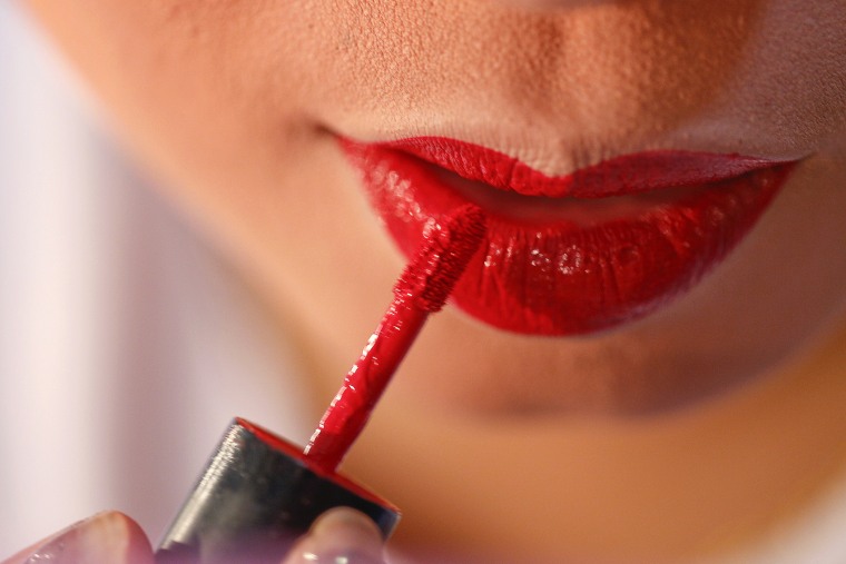 A woman applies applies red lipstick. (Photo by Athit Perawongmetha/Reuters)