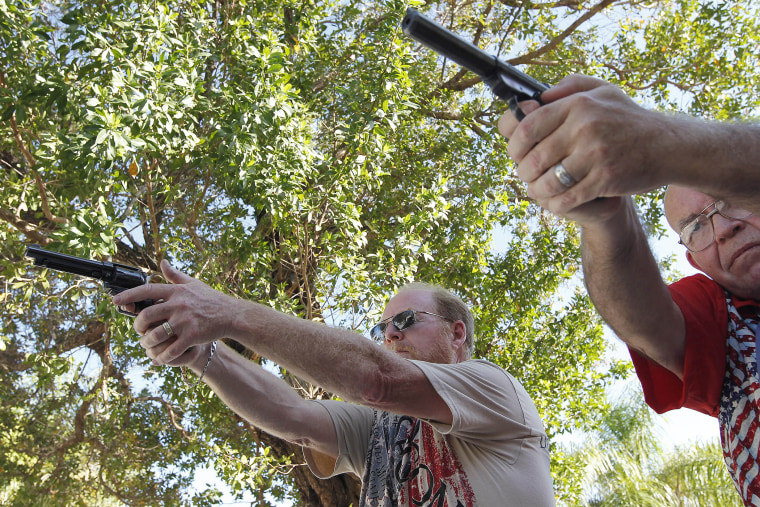 Varrieur and Gordon practice their firing stance with unloaded weapons in the yard of Varrieur's home in Big Pine Keys. (Photo by Andrew Innerarity/Reuters)