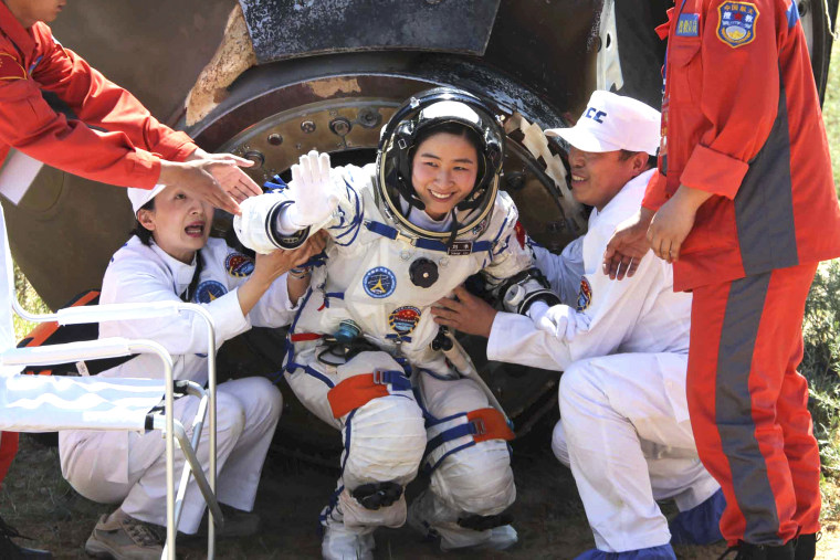 In this photo released by China's Xinhua news agency, China's first female astronaut Liu Yang waves as she comes out of the re-entry capsule of Shenzhou-9 spacecraft in Siziwang Banner of north China's Inner Mongolia Autonomous Region, June 29, 2012.