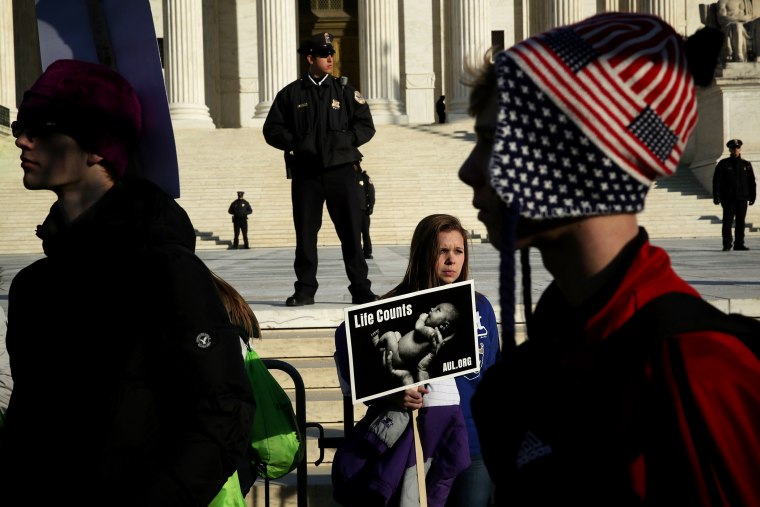 A pro-life activist holds a sign as she watches the annual March for Life passes by in front of the U.S. Supreme Court Jan. 22, 2015 in Washington, DC. (Photo by Alex Wong/Getty)