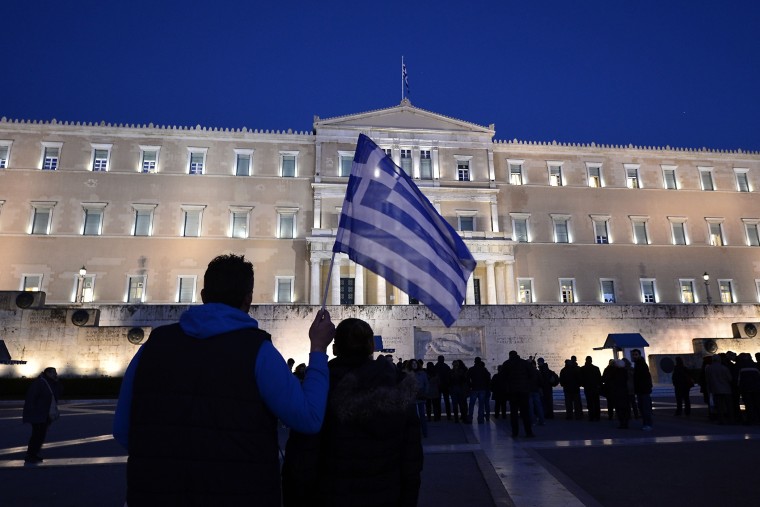 A man holds a Greek flag in front of the Greek parliament in Athens as people gather in support to their government on Feb. 20, 2015.