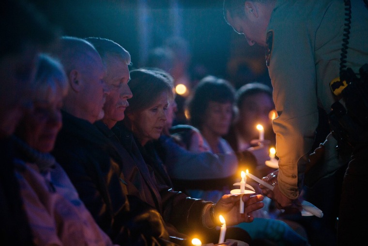 Carl and Marsha Mueller hold candles being lit during a vigil at a candlelight memorial honoring aid worker Kayla Mueller in Prescott, Ariz. on Feb. 18, 2015. (Photo by Deanna Dent/Reuters)