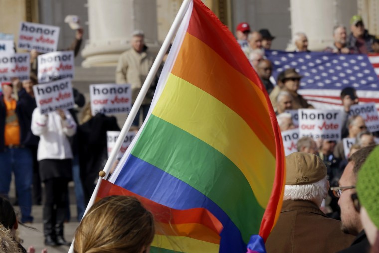Supporters of Arkansas' law banning same sex marriage, top, hold a rally as a protestor waves a rainbow flag at the Arkansas state Capitol in Little Rock, Ark. on Nov. 19, 2014.