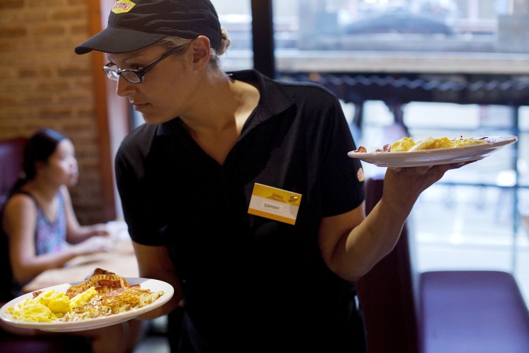 Waitress Sarah Ortiz delivers a tray of food to customers at a Denny's restaurant in New York, on Sept. 6, 2014.