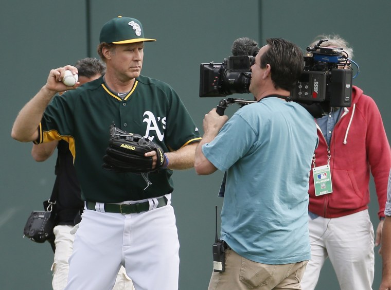 Actor Will Ferrell, left, warms up for the Oakland Athletics prior to the first inning of a spring training baseball game against the Seattle Mariners, on March 12, 2015, in Mesa, Ariz.