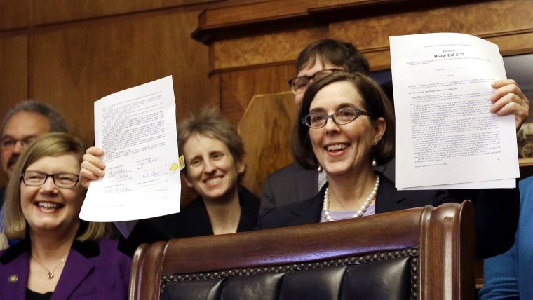 Oregon Gov. Kate Brown holds up an automatic voter registration bill after signing it, on March 16, 2015, in Salem, Ore. (Photo by Don Ryan/AP)