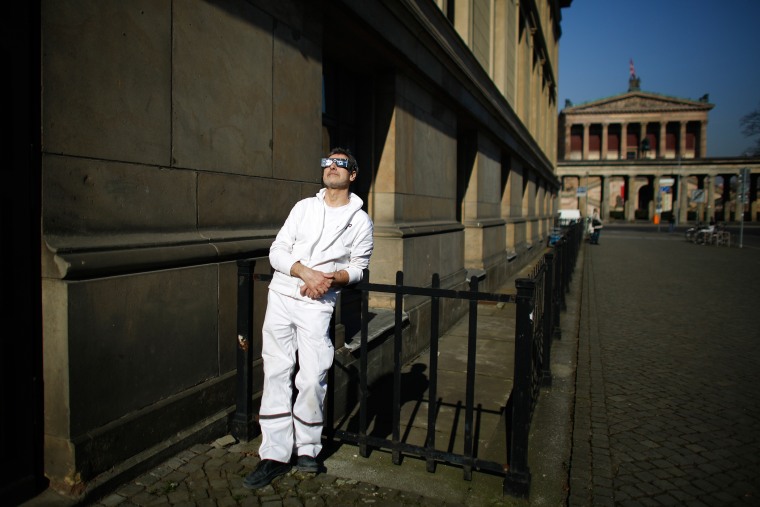 A man uses protective goggles as he watches the solar eclipse at the museums island in Berlin, March 20, 2015. (Photo by Markus Schreiber/AP)