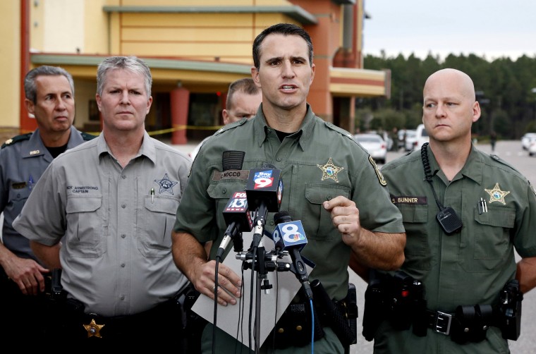 Pasco County Sheriff Chris Nocco (C) speaks to the media as police tape surrounds the Cobb Grove 16 movie theater, where a moviegoer shot and killed one person and wounded another, in Wesley Chapel, Fl., Jan. 13, 2014. (Photo by Mike Carlson/Reuters)