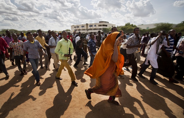 Members of the public run to get a glimpse as authorities display the bodies of the alleged attackers before about 2,000 people in a large open area in central Garissa, Kenya, April 4, 2015. (Photo by Ben Curtis/AP)