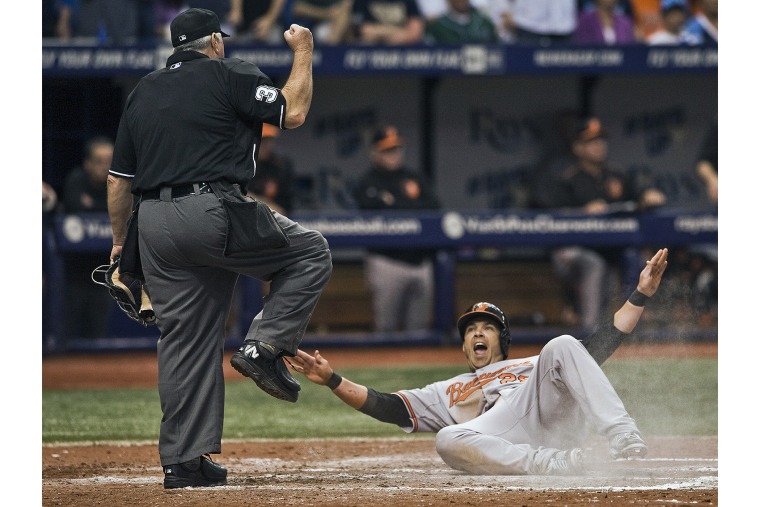 Baltimore Orioles' Steve Pearce signals he was safe on a play at the plate as umpire Dana DeMuth calls him out during the eighth inning of an opening day baseball game against the Tampa Bay Rays, April 6, 2015 in St. Petersburg, Fla. (Steve Nesius/AP)