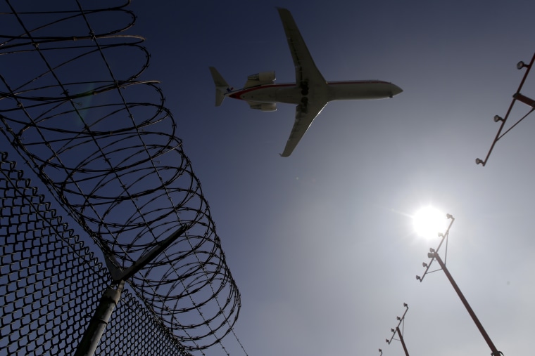 In this Feb. 6, 2015 photo, a passenger jet flies over the perimeter fence at the Los Angeles International Airport as it lands. (Photo by Chris Carlson/AP)