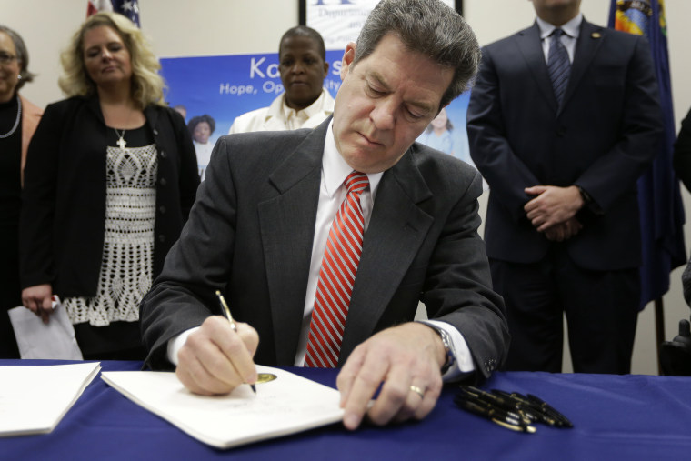 Gov. Sam Brownback signs a welfare reform bill into law in Topeka, Kan., April 16, 2015. (Photo by Orlin Wagner/AP)