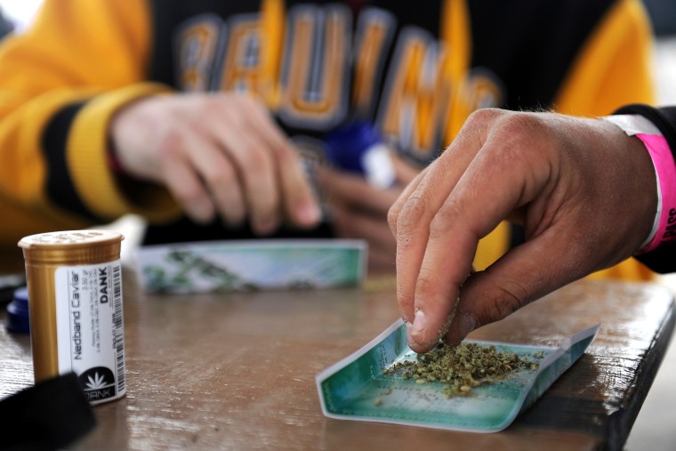 Shawn Holland, 21, breaks up a piece of marijuana to roll a joint during the High Times Cannabis Cup at the Denver Mart in Denver, Colo. on April 19, 2015.