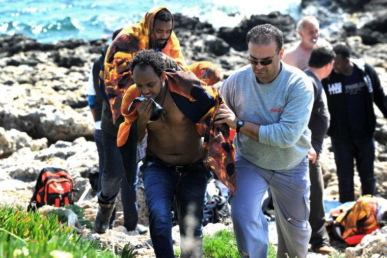 A Greek man helps a migrant to leave shore in the eastern Aegean island of Rhodes, Greece on April 20, 2015.