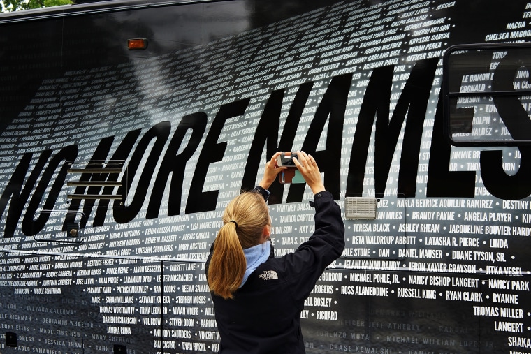 Lindsay Knauf takes a picture of a bus bearing some of the over 6,000 names of people killed by gun violence since the massacre in Newtown, six months after the massacre at Sandy Hook Elementary School on June 14, 2013. (Photo by Spencer Platt/Getty)