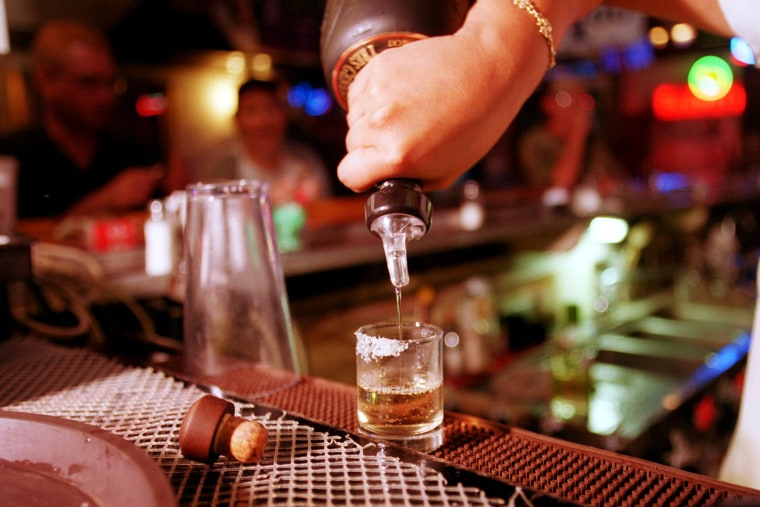 A shot of tequila is poured at a bar.