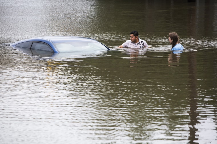 Roberto Salas, left, and Lewis Sternhagen check a flooded car on the frontage road between South Loop West Freeway and South Post Oak Road near the Willow Waterhole Bayou, May 26, 2015, in Houston.