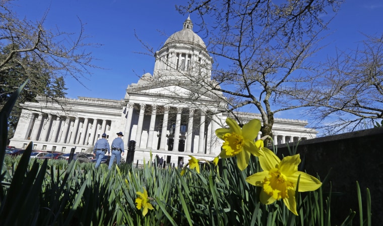 Early daffodils bloom as two Washington State Patrol troopers walk toward the U.S. Capitol, Feb. 17, 2015, in Olympia, Washington. (Photo by Ted S. Warren/AP)