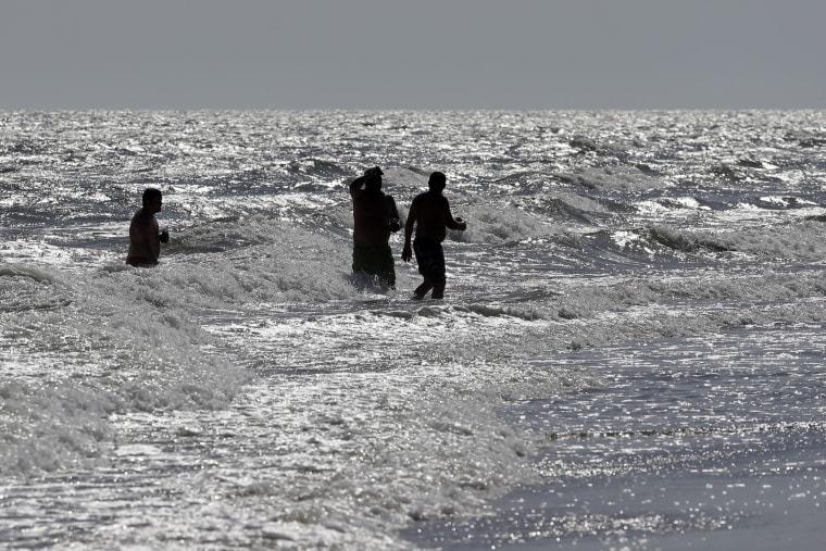 Vacationers walk in the surf in Oak Island, N.C. on June 15, 2015, the day after two separate shark attacks. (Photo by Chuck Burton/AP)