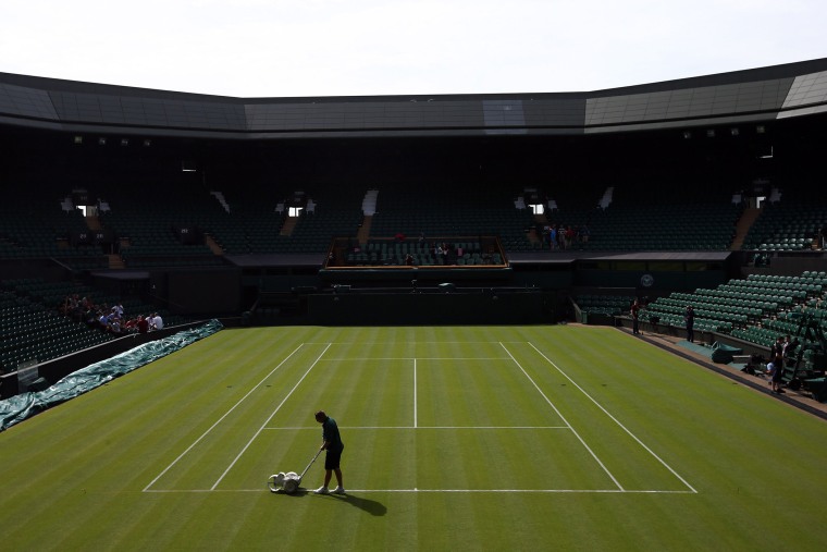 A groundsman paints a line on Centre Court on day 1 of the Wimbledon tennis tournament on June 29, 2015 in London, England. (Photo by Carl Court/Getty)