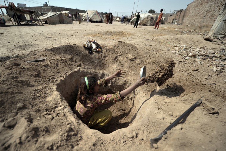 A Pakistani child digs a hole to be used as a toilet for her family at a slum in Multan on March 13, 2012. (Photo by Bay Ismoyo/AFP/Getty)