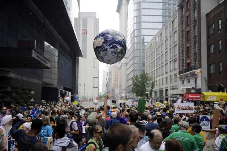 A man holds an earth balloon into the air as people fill the street before a global warming march in New York Sunday, Sept. 21, 2014. (Photo by Mel Evans/AP)