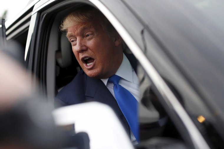 Republican presidential candidate Trump speaks to the media through his SUV window after a rally in Manchester