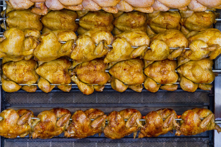 chickens are grilled on spits in rows on a grill. (Photo by Frank Bienewald/LightRocket/Getty).