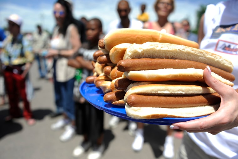 A man carries a plate of hot dogs in preparation for a hot dog eating contest. (Photo by Hyoung Chang/The Denver Post/Getty).