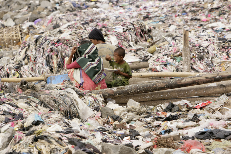 A child eats lunch beside his parents at a garbage dump site in Jakarta, Indonesia on Mar. 25, 2008 (Photo by Beawiharta Beawiharta/Reuters).