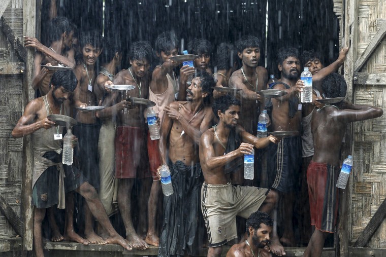 Migrants, who were found at sea on a boat, collect rainwater during a heavy rain fall at a temporary refugee camp in Myanmar on Jun. 4, 2015 (