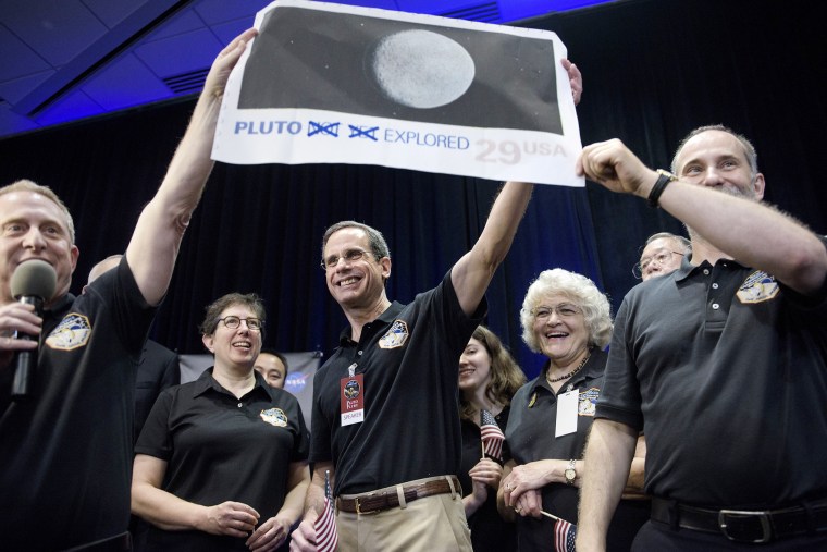 Dr. Allan Stern and others hold up their suggestion for a modified US Post Office stamp of Pluto at the Johns Hopkins University Applied Physics Laboratory on July 14, 2015 in Laurel, Md. (Photo by Brendan Smialowski/AFP/Getty)