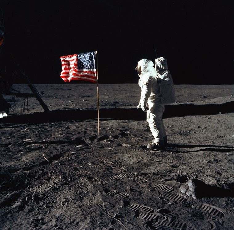 Astronaut Edwin E. Aldrin, Jr., the lunar module pilot of the first lunar landing mission, stands next to a United States flag July 20, 1969 during an Apollo 11 Extravehicular Activity (EVA) on the surface of the Moon.