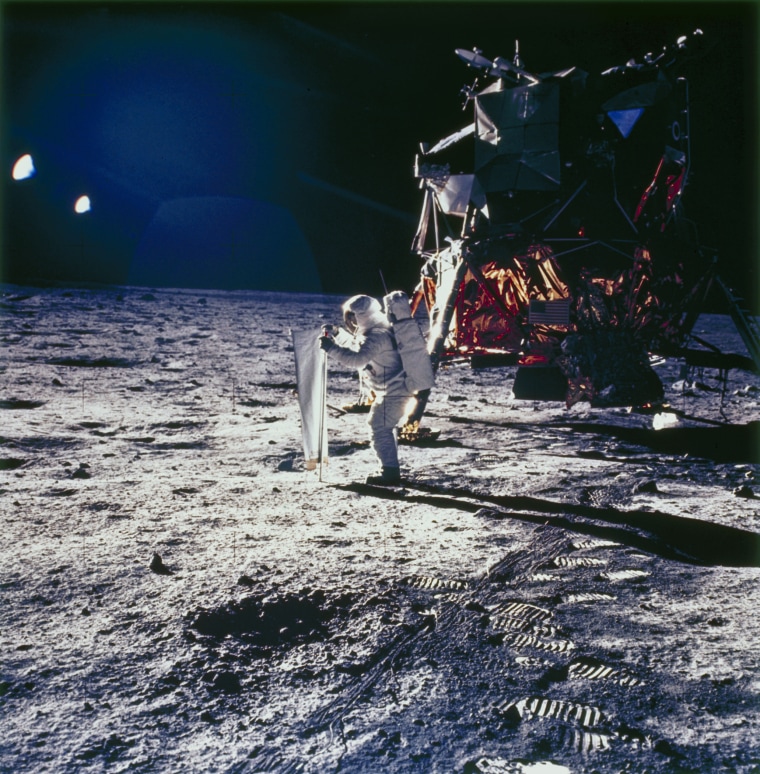 Aldrin is deploys the solar wind experiment on the lunar surface. The lunar module is in the background.