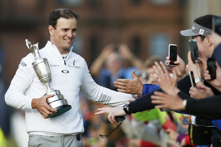 United States’ Zach Johnson celebrates with members of the public as he holds the trophy after winning a playoff after the final round at the British Open Golf Championship at the Old Course, St. Andrews, Scotland on July 20, 2015. (Photo by Jon Super/AP)