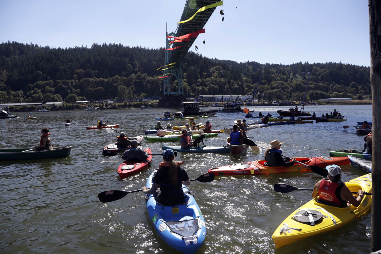 Kayakers gather as activists hang from the St. Johns Bridge in an effort to stop the Royal Dutch Shell PLC icebreaker Fennica from departing in Portland, Ore., July 30, 2015. (Photo by Don Ryan/AP)