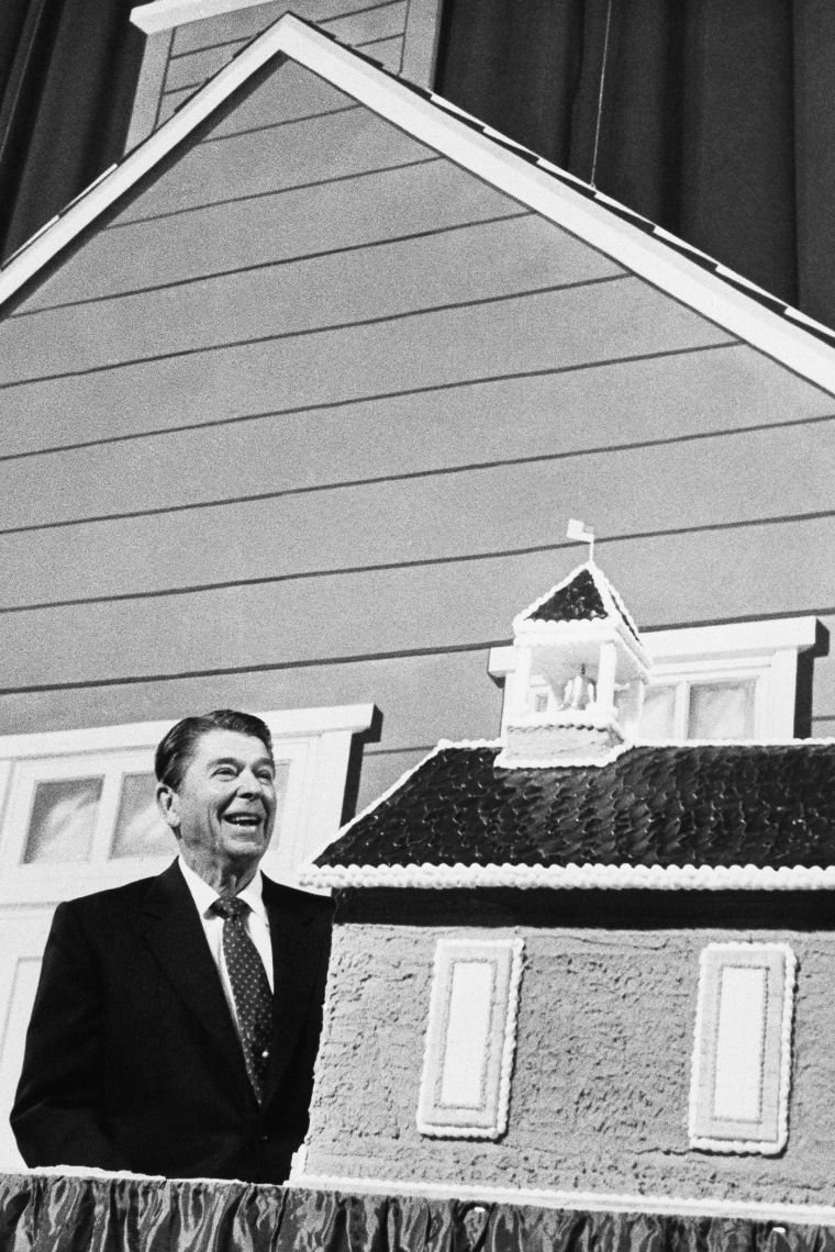 President Ronald Reagan looks over a 2 and a 1/2-foot high birthday cake in the shape of an old-fashioned red schoolhouse, Feb. 7, 1984 in Las Vegas, Nevada. (Photo by Dennis Cook/AP)