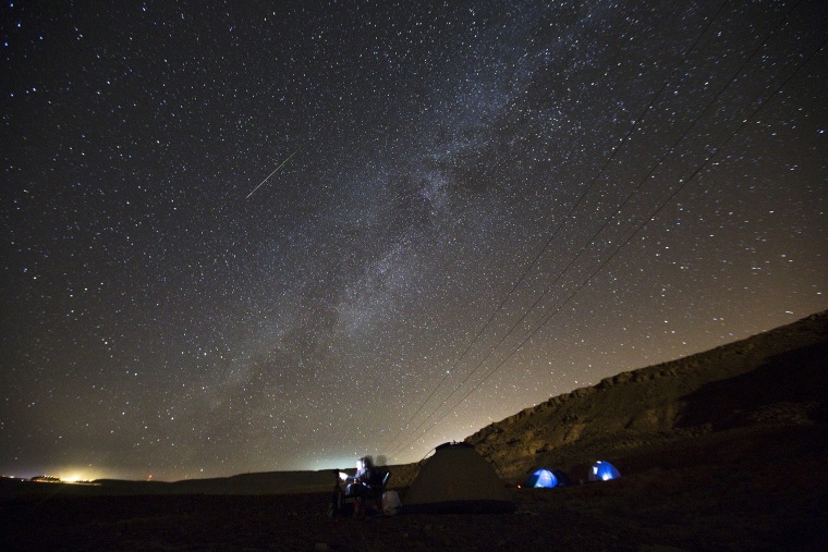 A meteor streaks across the sky in the early morning as people watching during the Perseid meteor shower in Ramon Carter near the town of Mitzpe Ramon, southern Israel, Aug. 13, 2015. (Photo by Amir Cohen/Reuters)
